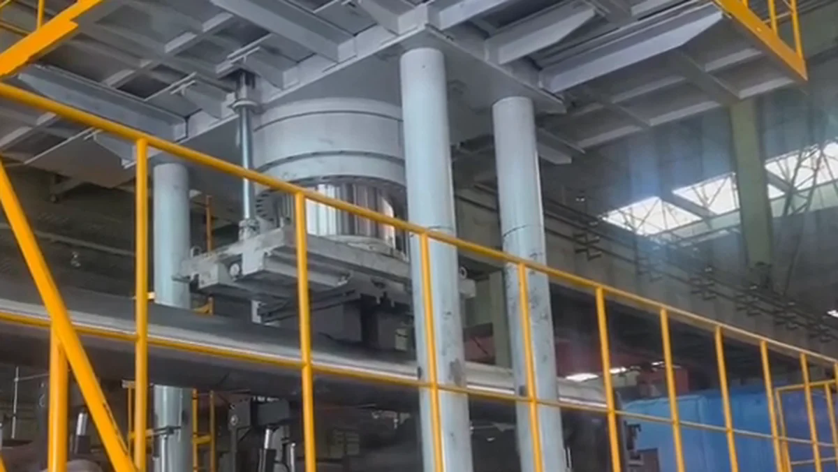Hydraulic press head positioned above a large steel pipe