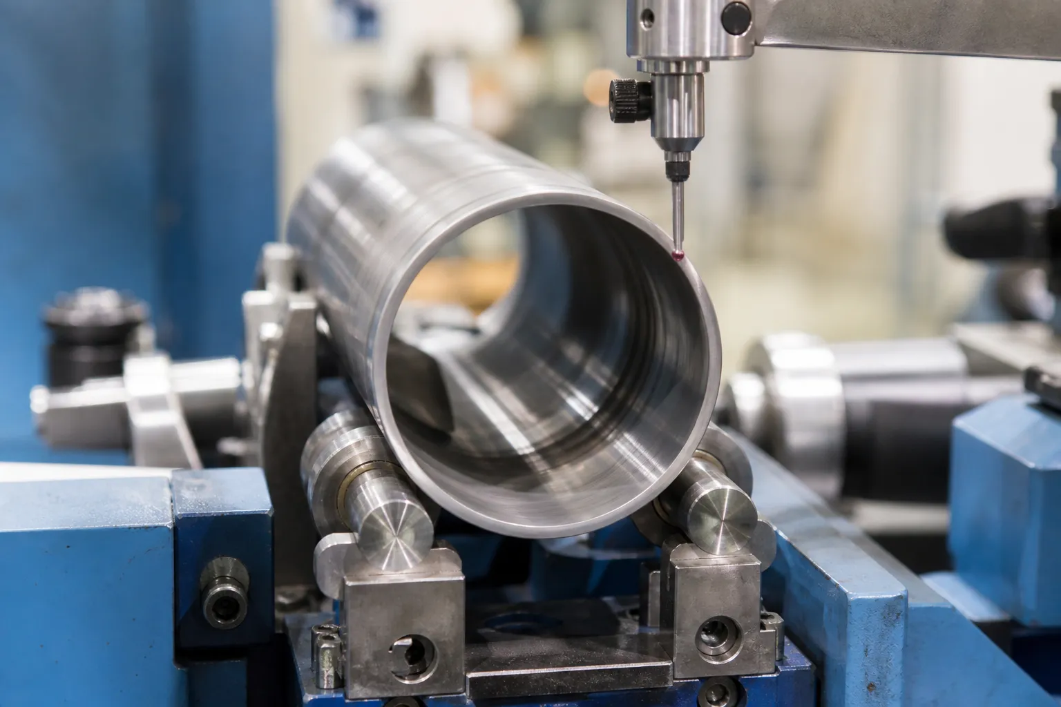 Ejector Sleeve Straightening Solution A thin-walled tubular steel sleeve rotating on precision rollers under a probe measuring wall concentricity